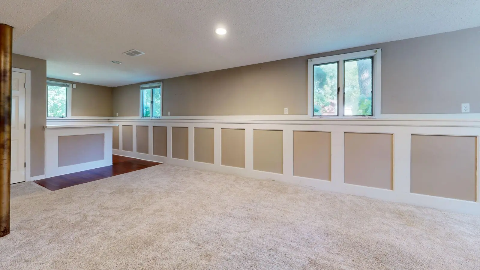 Finished basement room with carpet and windows set high in the wall